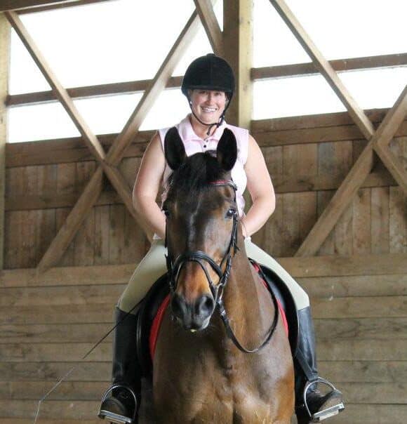 Smiling woman riding a dark bay horse