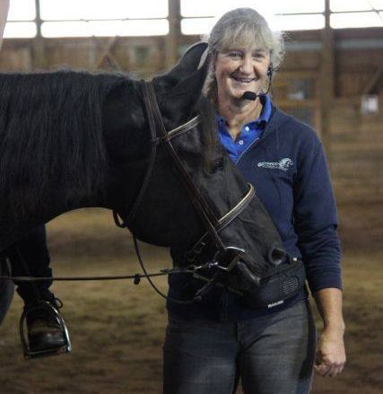 Standing with Briosa Anne Gage The Horse Riding Confidence Coach stands with a black horse at a clinic
