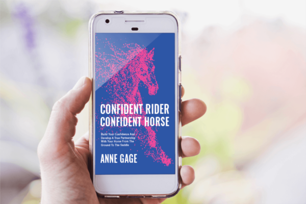 Hand holding a smart phone displaying Confident Rider Confident Horse pdf book